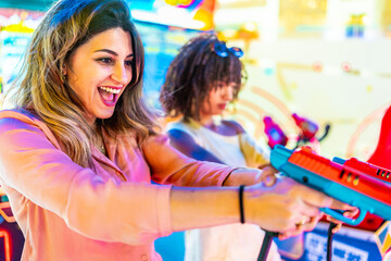 Excited friends playing arcade games on summer vacation