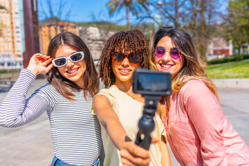 Three happy friends taking selfie with action camera during summer vacation
