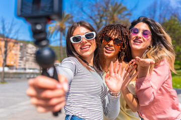 Happy friends taking selfie with gimbal in the city during summer vacation
