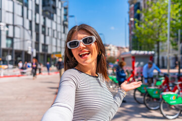 Young woman taking selfie showing city in summer