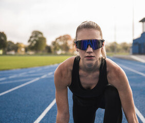 Young athlete wearing smart glasses at starting line of track