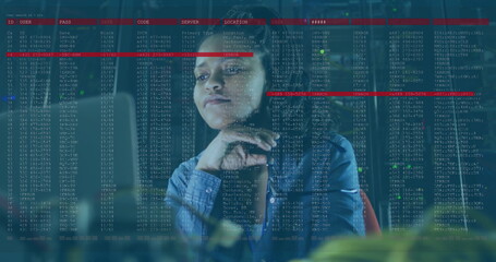 Mid adult blue-shirted woman studying code on glass panel at office, with monitors and keyboard