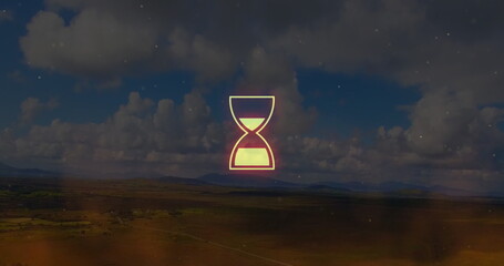 Glowing neon hourglass hovering above fields and hills under cumulus clouds, with particle overlay