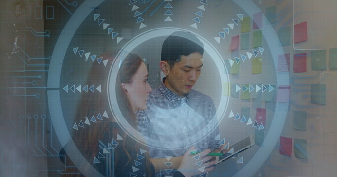 Collaborating coworkers in blazers reviewing sticky notes at creative office with tablet and HUD