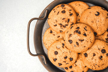 Freshly baked chocolate chip cookies served in a round metal tray