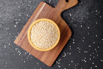 Quinoa seeds in wooden bowl on cutting board
