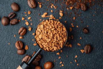 Instant coffee granules in scoop with coffee beans