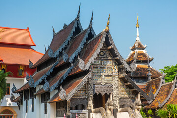 Ornate wooden Thai temple with intricate carvings under clear blue sky in Chiang Mai, Thailand. Buddhist temple. Thai religious architecture. Travel and touristic landmark © samael334