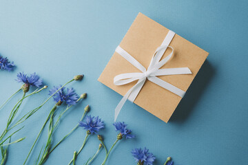 Gift box with cornflowers on blue background