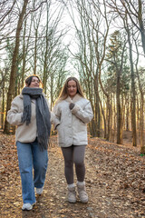 Two female friends on a walk in the forest. Friends walking through the forest. People in nature.