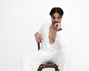 sexy fashion model in white costume sensually touching lips while sitting