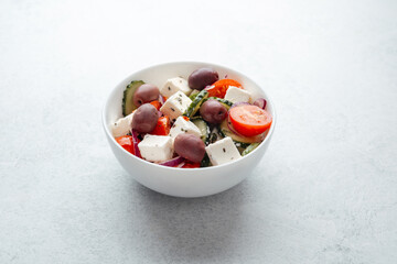 Greek salad with feta cheese olives cucumbers and tomatoes in white bowl