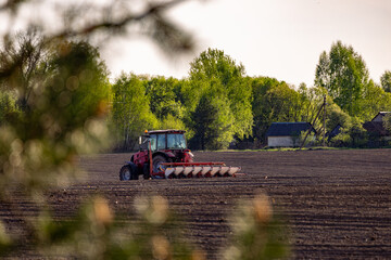 Tractor plowing field at sunset. Red tractor plowing, cultivating soil. Plow on plowed. Farm...