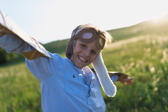 A small boy playing on a meadow in nature, with goggles and wings as if flying. - Powered by Adobe