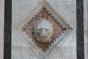 A carved lion's head adorning the exterior of the Duomo di Siena, Italy