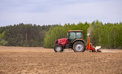 Tractor drilling seeding crops at farm field. Agricultural activity. Tractor spraying pesticides at...