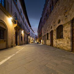 Twilight casts a soft glow over the narrow alleys of Siena,  where historic buildings and elegant facades create an emotive and timeless urban scene. Travel to Tuscany, Italy.