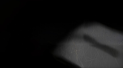A black and white photo of a dark room. A small area is illuminated, revealing a weathered cement texture