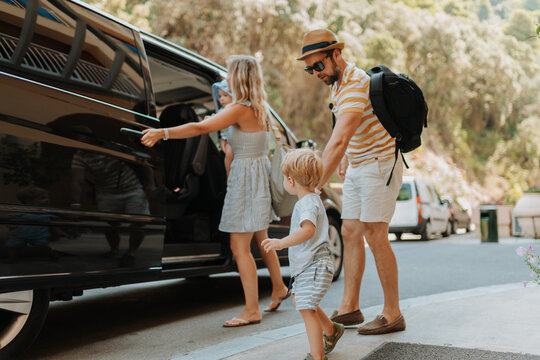 Parents with toddlers boarding car for airport transfer or holiday trip - Powered by Adobe