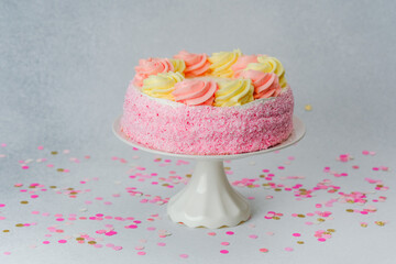 Delicious pink and yellow frosted cake on display with colorful confetti