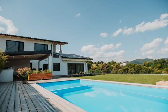 Modern house with swimming pool in backyard on sunny day