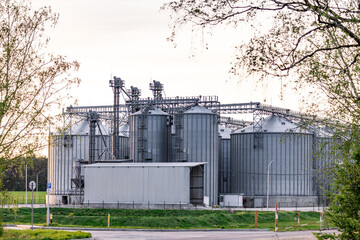 Large metallic storage tanks and silos are situated within an industrial complex, showcasing a...