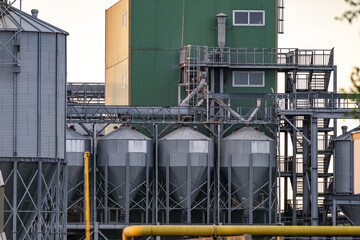 Large metallic storage tanks and silos are situated within an industrial complex, showcasing a...