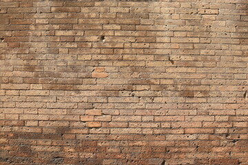A detailed close-up of an old red brick wall in Siena, Italy