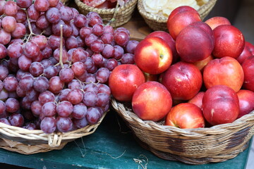 Red grapes and peaches in a wicker basket on sale