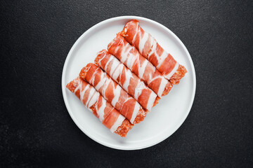 Minced meat rolls wrapped in bacon on white plate