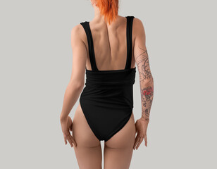 Template of a black one-piece swimsuit on a red-haired slim girl with a tattoo, for design, print, branding.