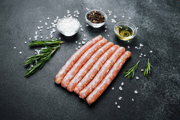 Raw sausages with spices on black stone table