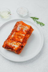 Marinated pork ribs on white plate with rosemary and spices