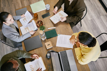 High angle shot of diverse group of young adult and middle aged men and women discussing financial...