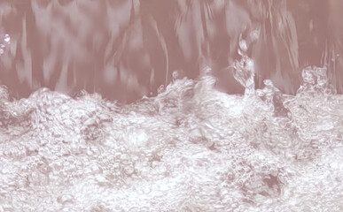 ピンク色の川面に落ちる水しぶきの写真