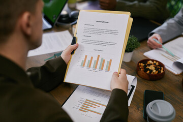 Close up on marketing document representing target audience statistics in graphs and pen lying on...