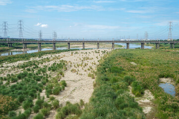 River landscape with exposed bed and distant infrastructure. Wide river area with limited water...