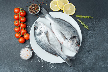Raw dorado fish with tomatoes lemon herbs and spices on white plate