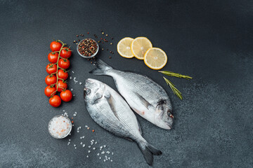 Fresh raw dorado fish with tomatoes lemon and spices on black background