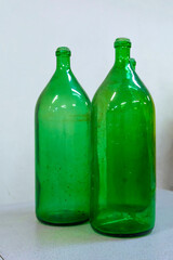 Three large green glass wine bottles on a table with a light surface. The texture of the glass is...