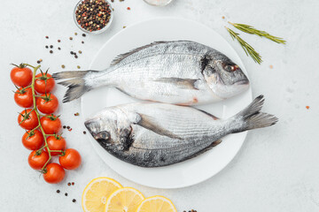 Raw dorado fish with tomatoes lemon and spices on white background