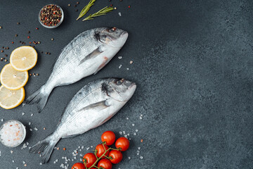 Top view of raw dorado fish with lemon pepper and rosemary on black background