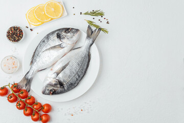 Close up of two dorado fish on white plate with lemon and tomato