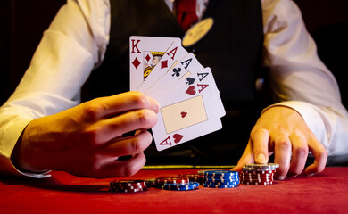 Player opens playing cards with one pair or two aces on red poker table. Close-up of playing chips...