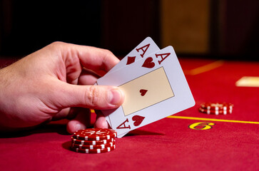Two aces and big stake on red felt. Gaming cards in hand. Poker chips with two aces on background....