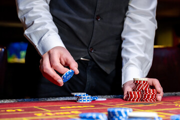 A man places a bet with chips in a casino. A player takes a lot of chips in a casino .Poker game in...