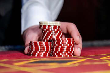 A man places a bet with chips in a casino. A player takes a lot of chips in a casino .Poker game in...