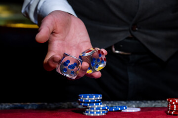 Gambling concept. Close up of male hand throwing dice at casino, gambling club. Casino chips or...