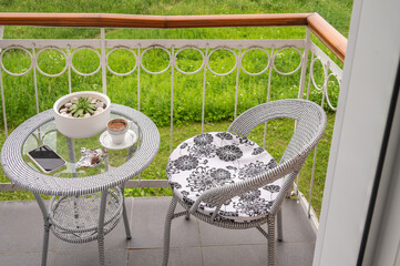 A cup of coffee, a smartphone on a glass table on a balcony.	