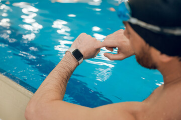 Man having a workout in the swimming pool and looking at his watch